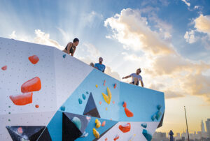 three teens sitting at the top of a climbing wall