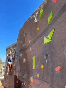 young girl almost to the top of a climbing bolder